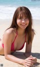 A woman in a red bikini laying on the beach.