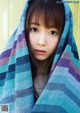 A young woman wrapped in a blue and purple blanket.