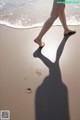 A person walking on a beach with their shadow on the sand.