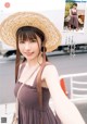 A woman in a brown dress and a straw hat.