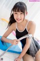 A young girl in a bathing suit is playing with a shower head.