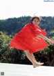 A woman in a red dress is jumping in the air.