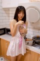 A woman in a white dress holding a jar of flowers.