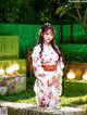 A woman in a white kimono sitting on a stone wall.