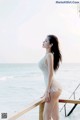 A woman in a white bathing suit standing on a pier by the ocean.